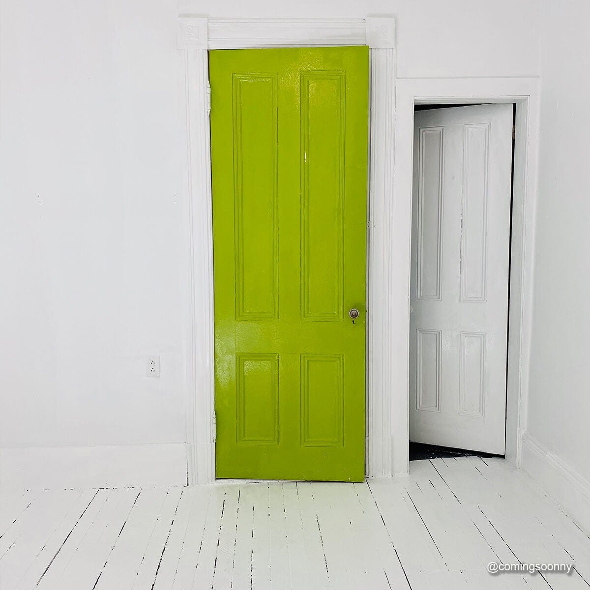 A door painted with PRETTY UGLY in an all-white room