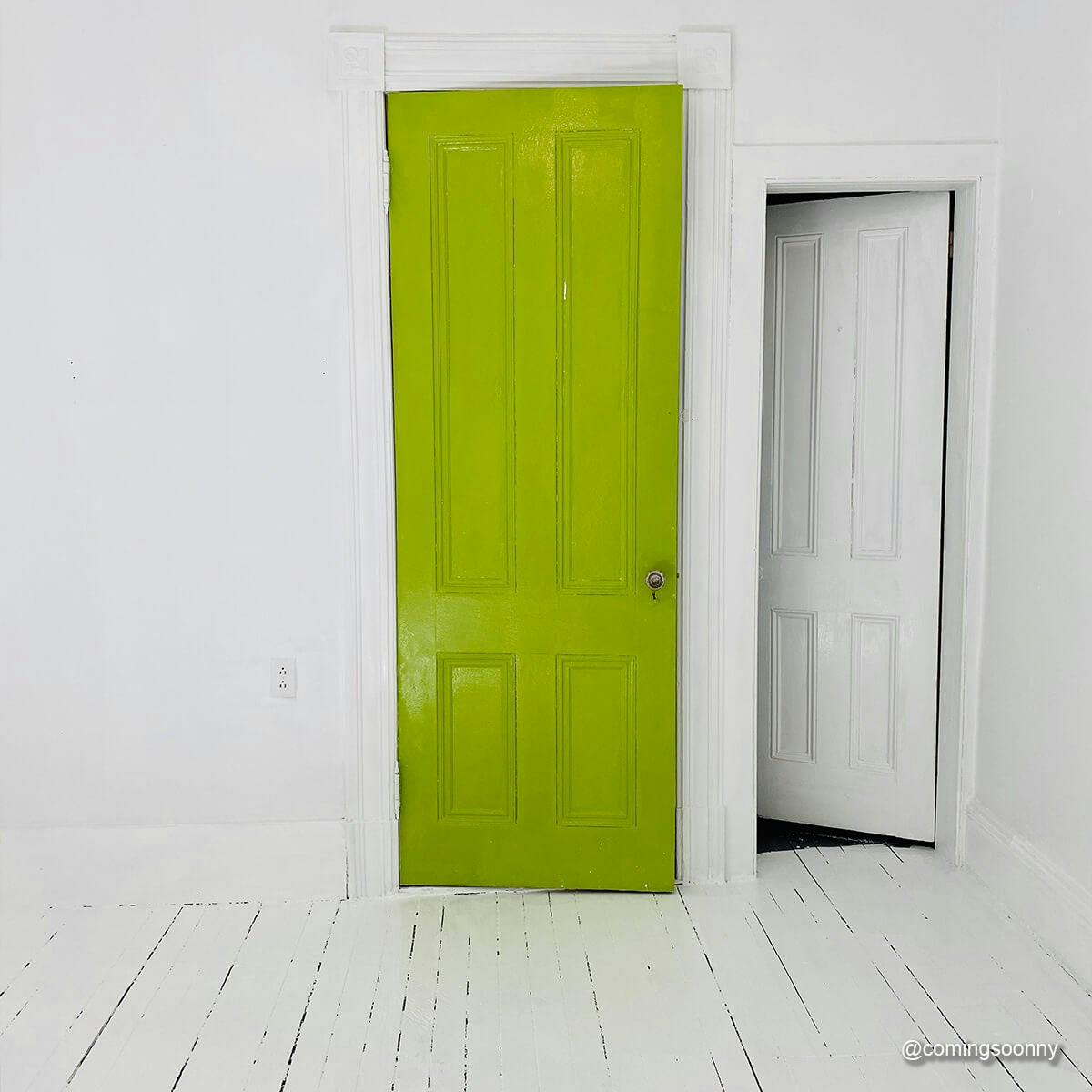 A door painted with PRETTY UGLY in an all-white room