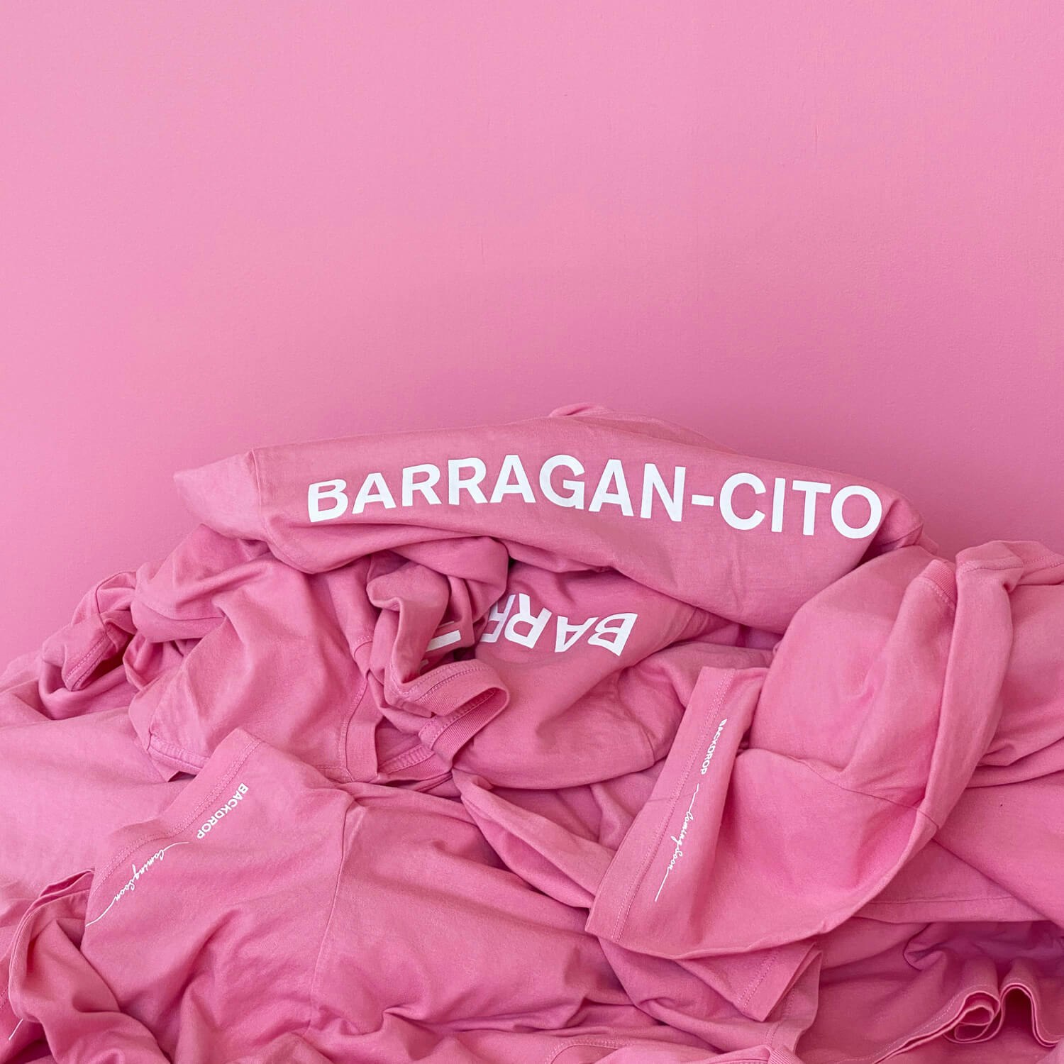 BARRAGÁN-CITO painted on a wall with pink t-shirts in front of it