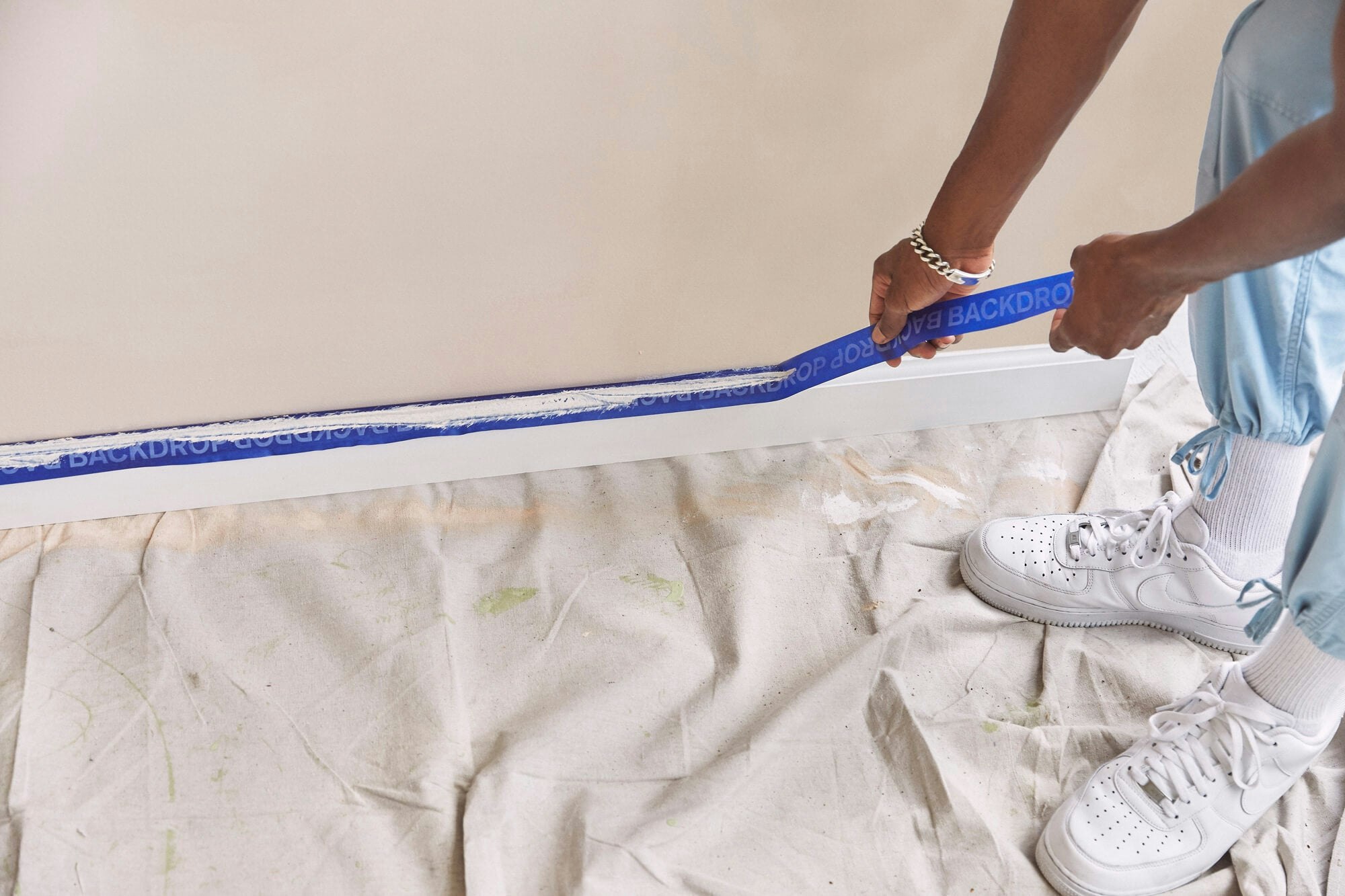 A pair of hands removing painter's tape from floor trim