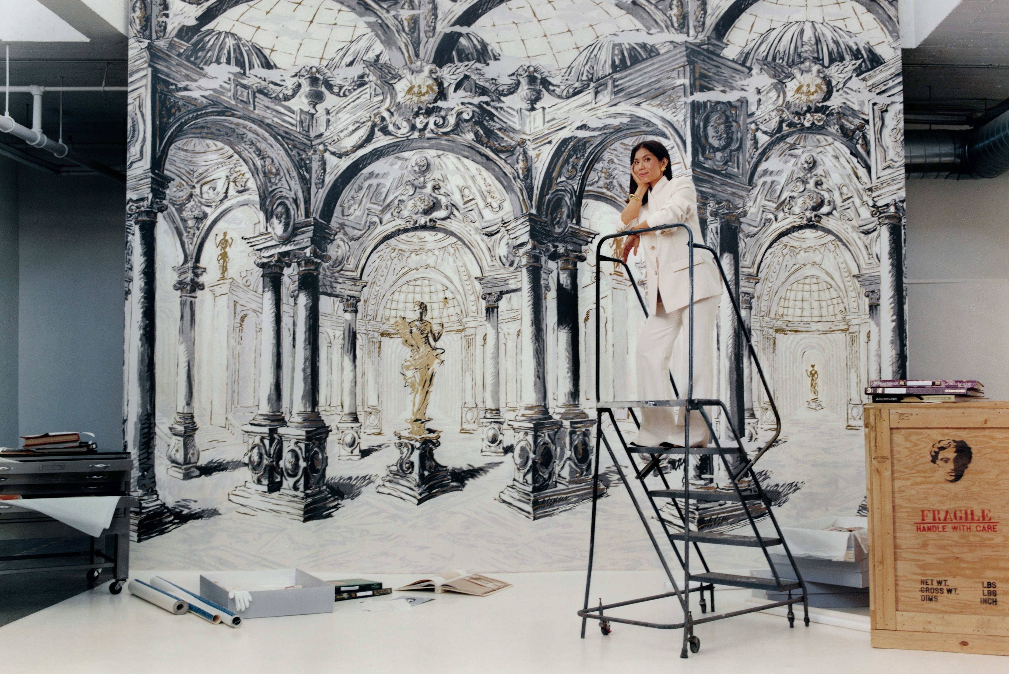 Backdrop's founder in front of a new wallcovering, PALAZZO, a four piece panel set that appears an a museum-like space